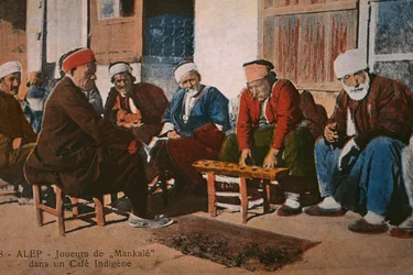 Postkarte, die Mancala-Spieler in einem Café in Aleppo, Syrien, ca. 1920 zeigt (Farbphotolithografie)