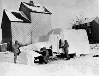 Zweiter Weltkrieg (1939-1945): In der Nähe von Bastogne (Belgien) Ende Dezember 1944: Diese amerikanischen Soldaten verwenden weiße Laken, um einen Lastwagen vor den Augen des Feindes zu verbergen