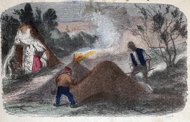 Herstellung von Holzkohle im 19. Jahrhundert: Köhler vor Mühlsteinen aus Holz und Lehm, die sie anzünden. Gravur Ende des 19. Jahrhunderts.