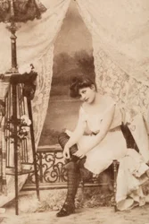 Porträt einer jungen Frau in intimer Kleidung, die sitzt und ihren Schuh schnürt