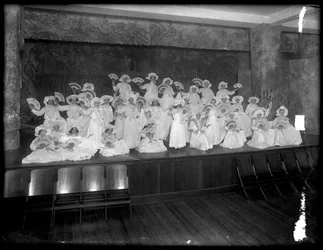 Gruppe kleiner Mädchen auf einer kleinen Bühne mit Fächern, wahrscheinlich das römisch-katholische Waisenhaus, Kingsbridge, Bronx, ca. 1911